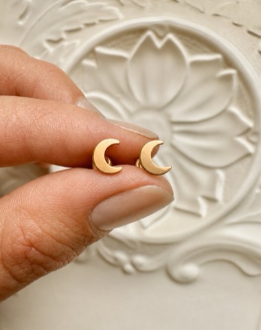 Harvest moon studs, tiny gold filled crescent moons, held between two fingers